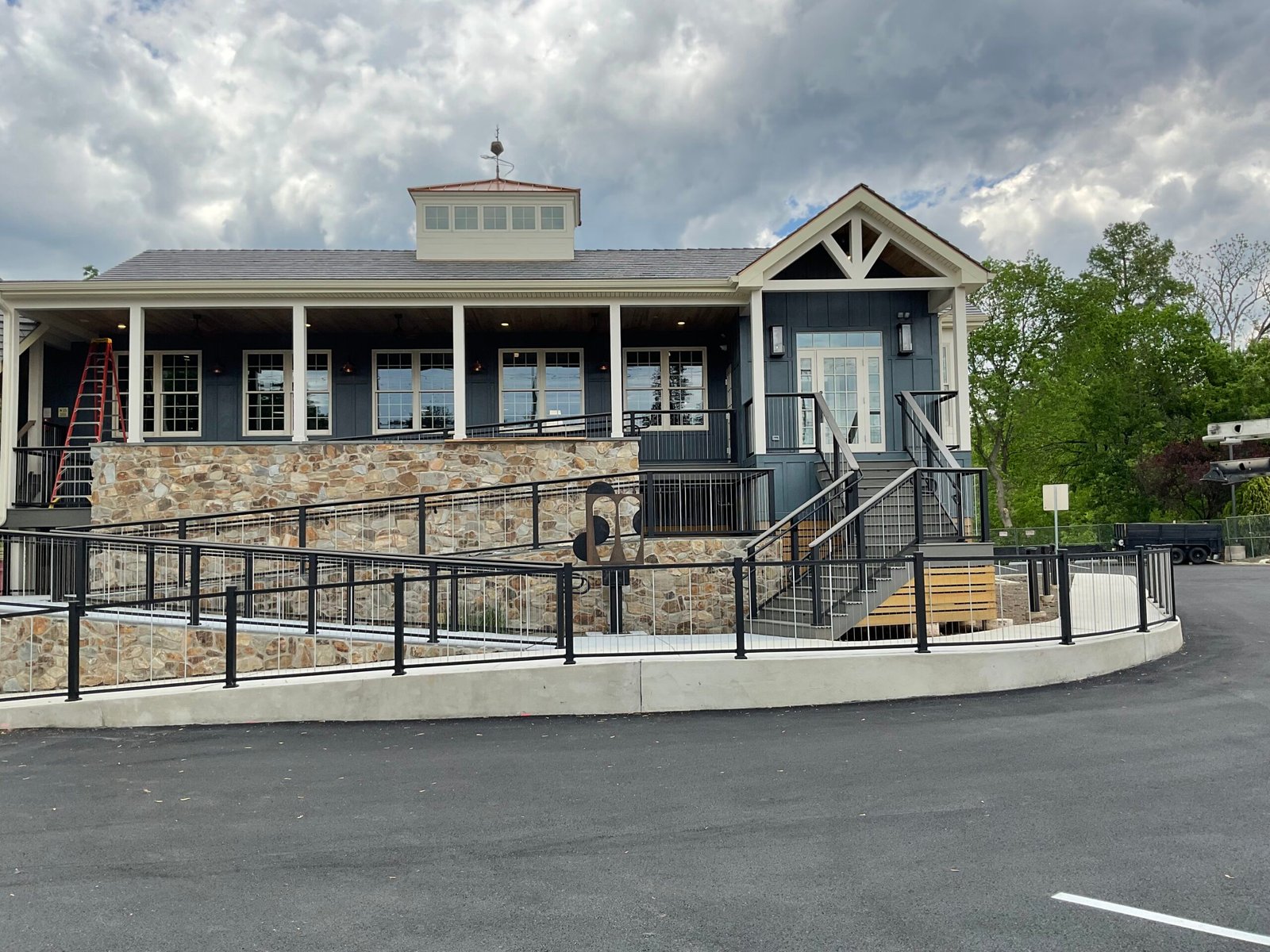 Blue commercial building with stone base, wraparound porch and black railing