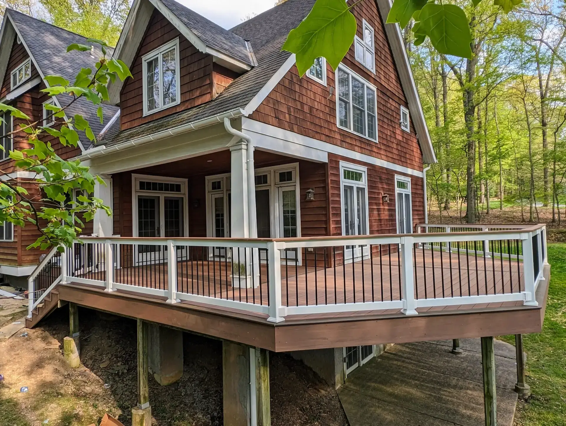 Elevated composite deck with white railing on a red cedar-shake home