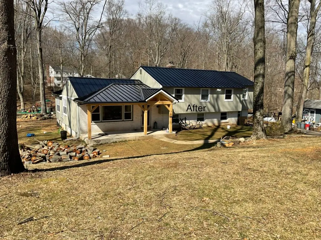 Gray home with black metal roof and timber entry - Skyline Exteriors - Skyline Exteriors Gray two-story home with black metal roof and timber-frame entry on a wooded lot