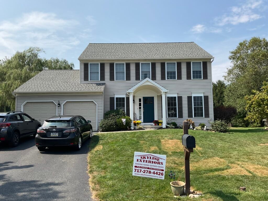 Tan colonial with new shingle roof and yard sign - Skyline Exteriors - Skyline Exteriors Tan colonial home with new dark shingle roof and Skyline Exteriors yard sign