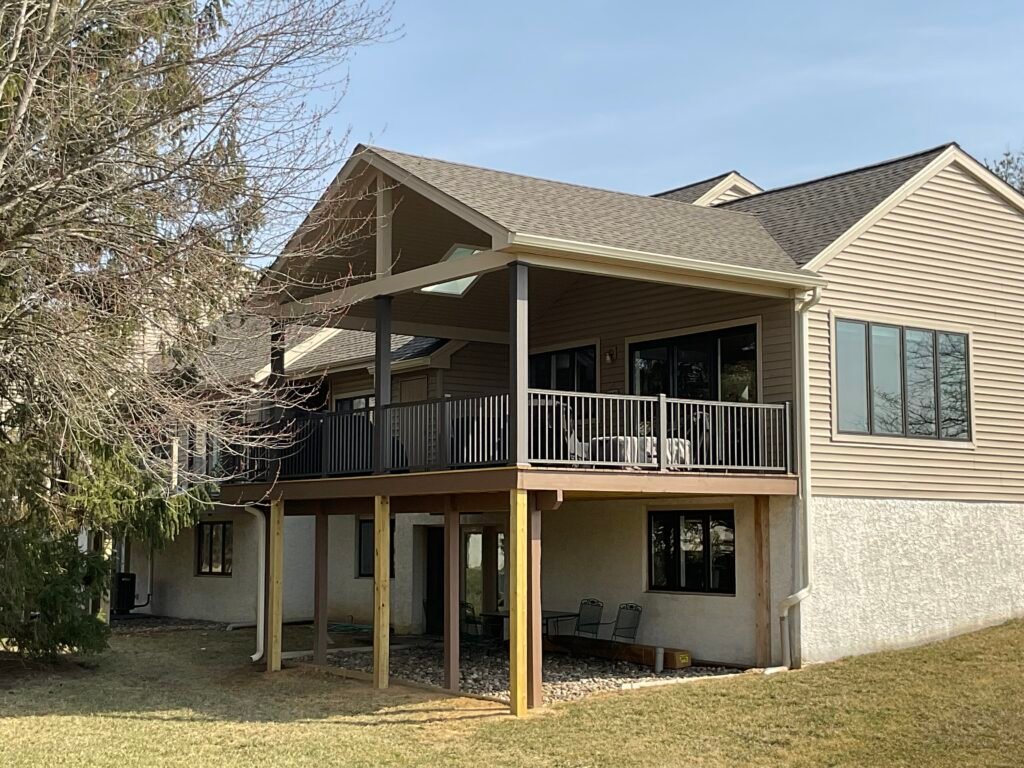 Two-story covered deck and porch addition - Skyline Exteriors - Skyline Exteriors Tan home with new two-story covered deck and porch addition