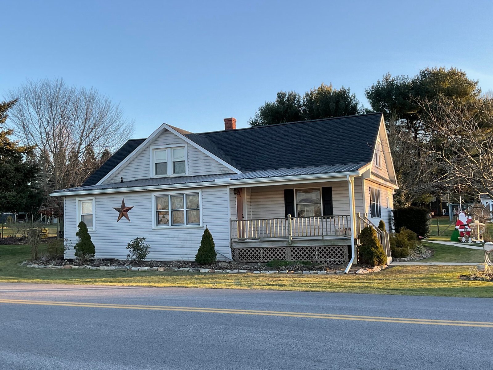 White farmhouse with black standing-seam metal roof - Skyline Exteriors - Skyline Exteriors White two-story farmhouse with black standing-seam metal roof and porch