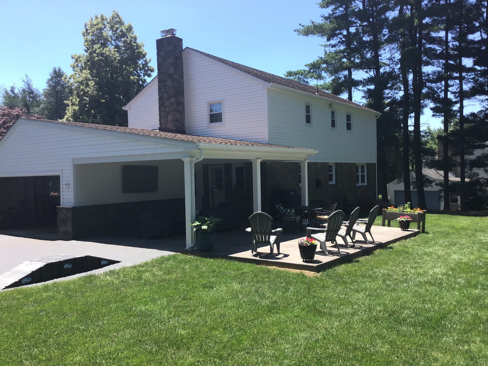 White home with covered back patio, black shingle roof and chimney