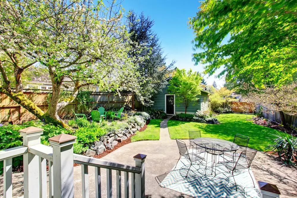 Backyard garden with stone patio and pergola - Skyline Exteriors - Skyline Exteriors Backyard garden with stone patio, pergola and white railing