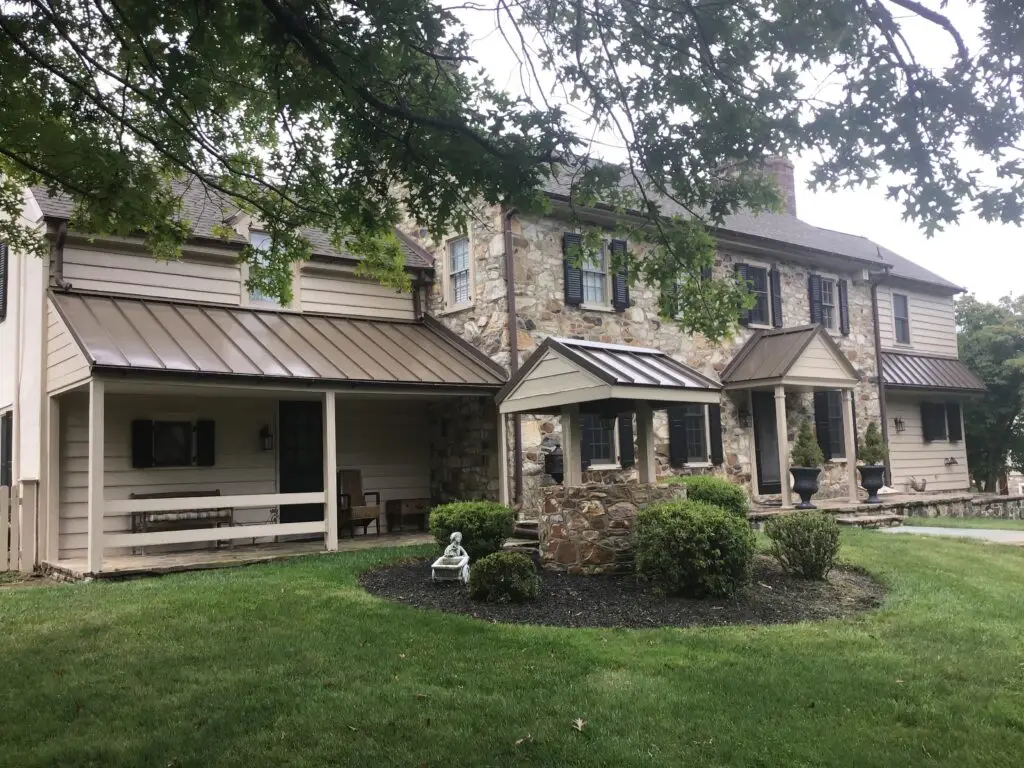 Stone two-story home with gray metal roof and front porch
