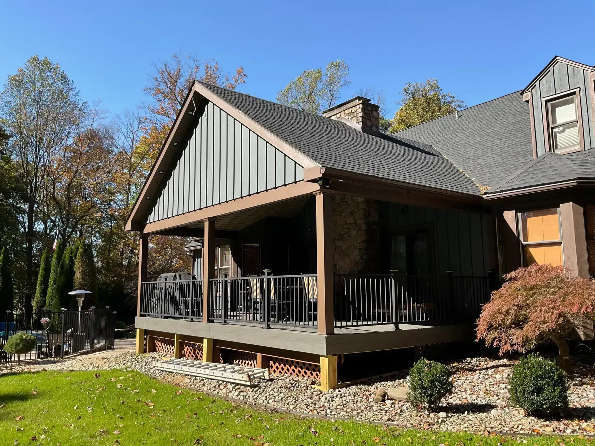 Board-and-batten home with new roof and patio - Skyline Exteriors - Skyline Exteriors Brown board-and-batten home with new roof and covered patio