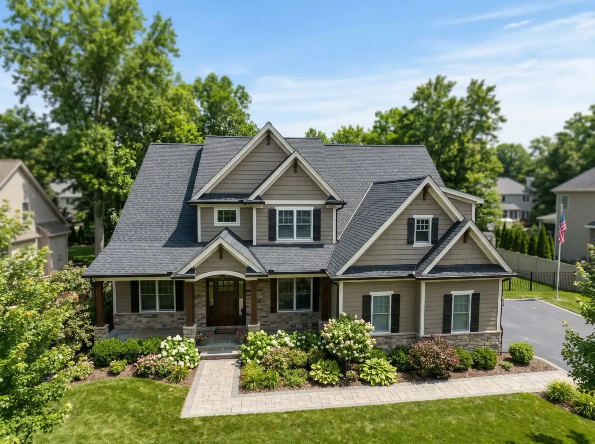 Two-story stone and siding home with gray architectural shingle roof