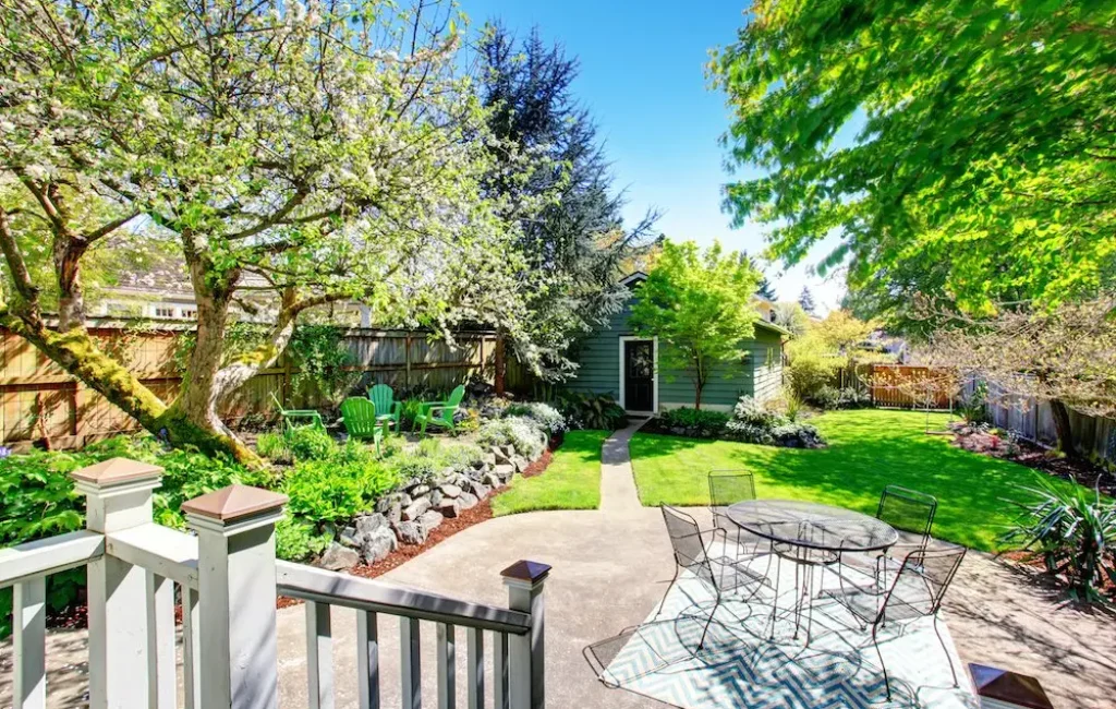Backyard garden with stone patio, pergola and white railing