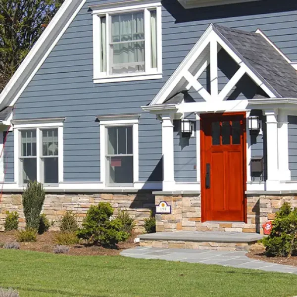 Blue vinyl-sided home with white trim and red front door