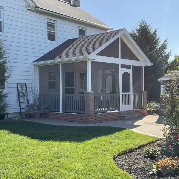 A custom screened porch addition on a white home built by an exterior remodeler in St. Davids, PA.
