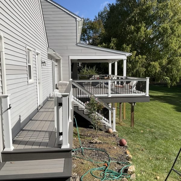 Side view of a gray home with elevated composite deck and stairs